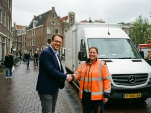 Zakelijke professional en logistiek coördinator schudden handen bij witte bestelwagen in Nederlandse straat